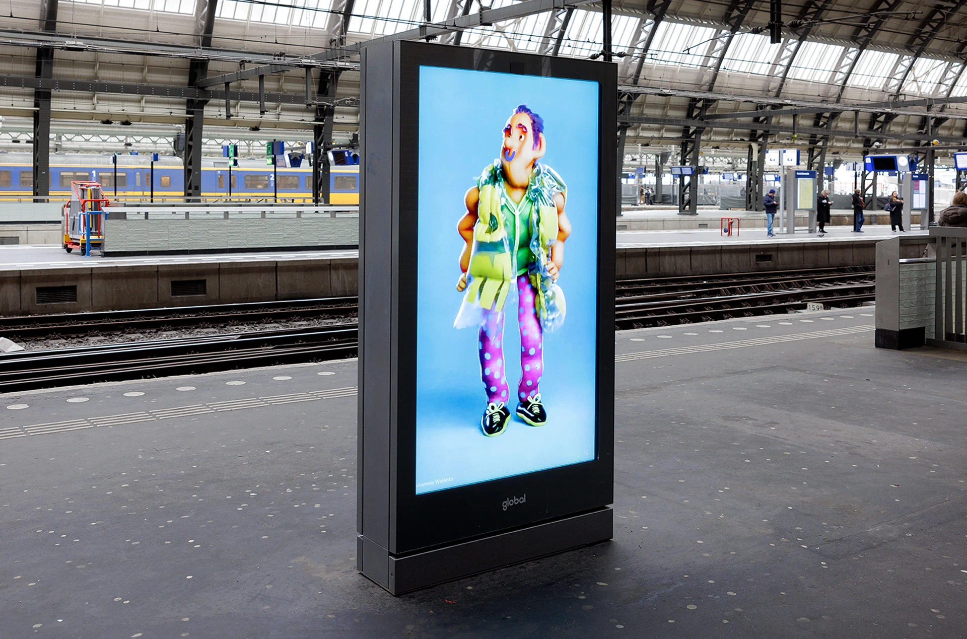 Personaje 3D sobre fondo azul en una pantalla de estación durante DEMO 2025