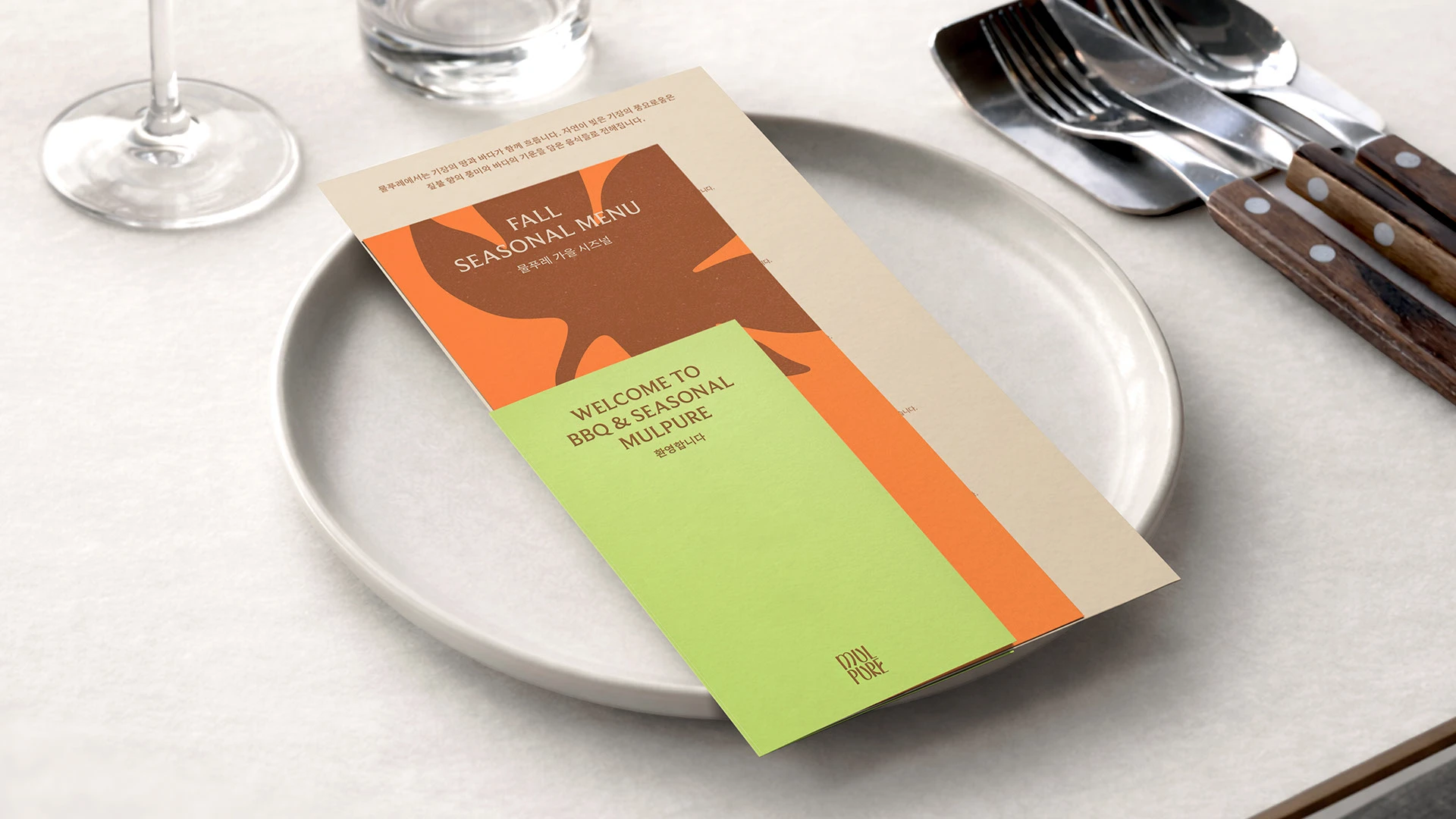 Carta de MULPURE sobre un plato con naranja verde y motivo gráfico de temporada